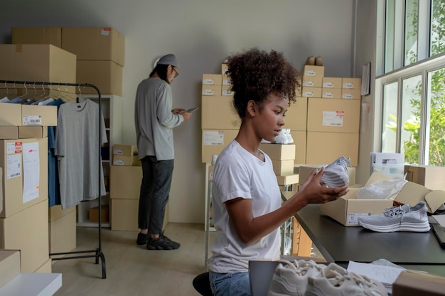 Mixed race couple of Asian man and AfricanAmerican woman online seller ecommerce business owner working together in store warehouse