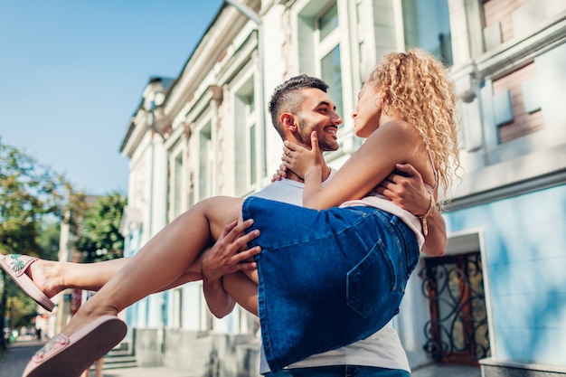 Mixed race couple in love walking in city. Arab man holding his girlfriend in hands. Young people hugging outdoors