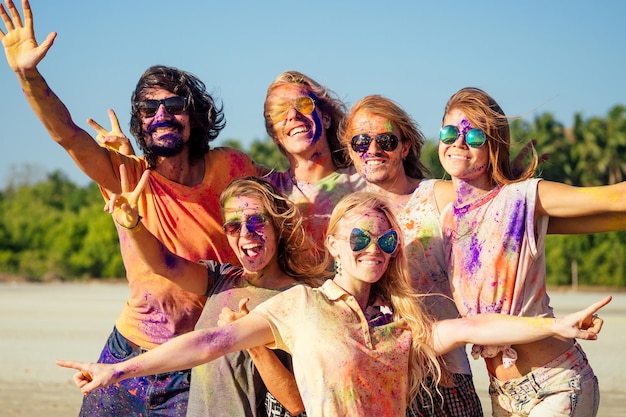 Mixed race friends having fun with colors on seaside outdoors in Goa India