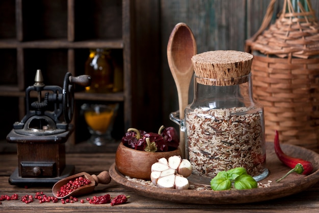 mixed rice in glass bottle with garlic and red hot chili pepper on wooden background