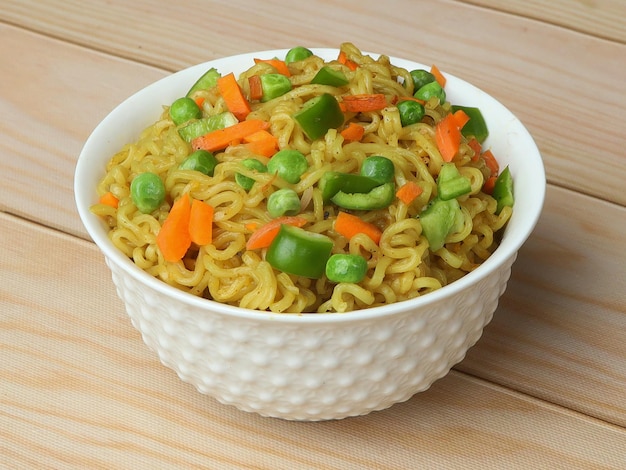 Mixed Veg Masala Maggie Noodles Instant Noodles cooked with veggies and then served in a bowl over a rustic wooden background selective focus