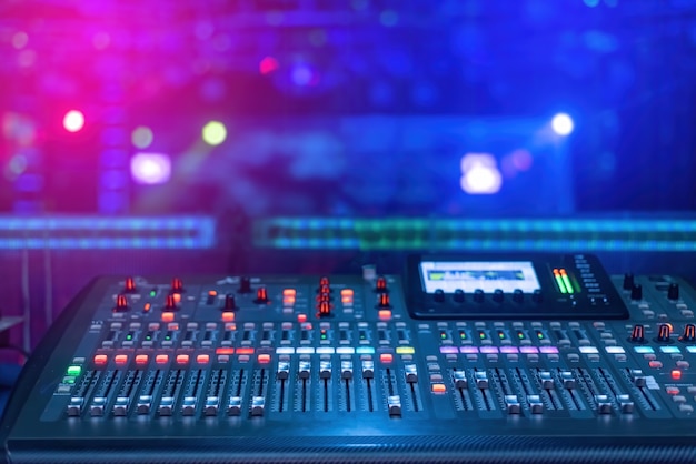 A mixer for mixing music with buttons and screen with blue and pink lights under low light conditions.