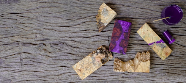 Mixing color purple epoxy resin in a glass cup for casting burl wood on old wooden table background