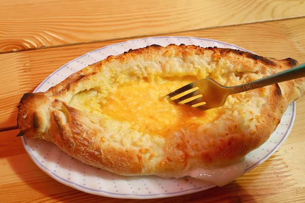 Mixing Egg and Cheese with Fork Before eating Adjaruli Khachapuri Georgian Bread