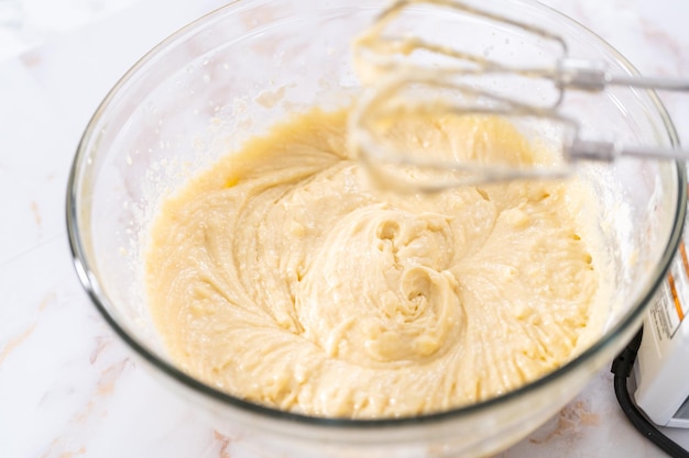 Mixing ingredients in a large glass mixing bowl to bake apple bundt cake with caramel glaze