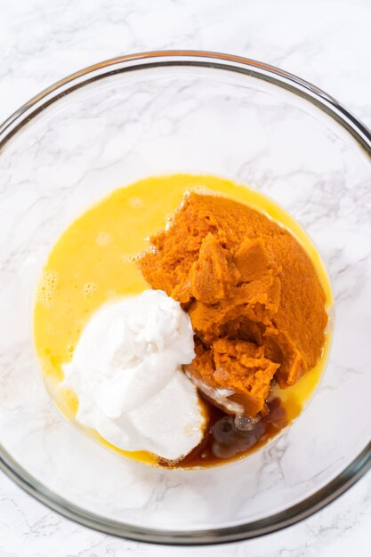 Mixing ingredients in a large glass mixing bowl to bake chocolate pumpkin bundt cake with toffee glaze.