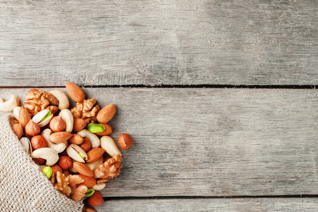 A mixture of fresh nuts spilled from a linen bag onto a gray wooden table