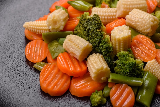 A mixture of vegetables carrots small heads of corn asparagus beans steamed