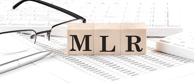 MLR Minimum Loan Rate written on wooden cube with keyboard calculator chartglassesBusiness concept