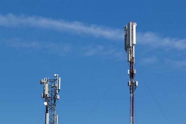 Photo mobile cell phone tower against the background of a blue sky and white cloud telecommunication tv