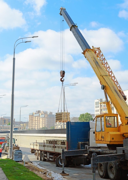 Mobile crane operating by lifting and moving an heavy cargo for road construction