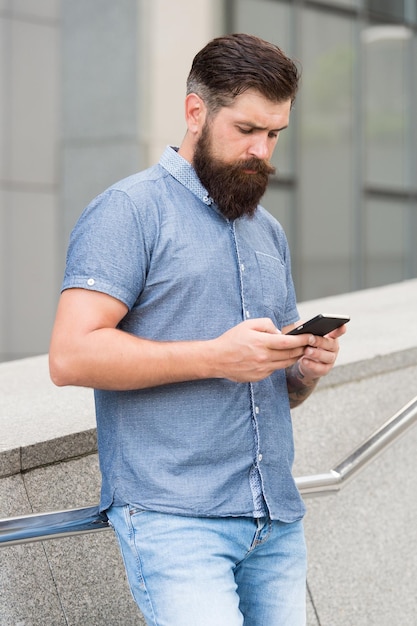 Mobile networks and broadband infrastructure. Bearded man text sms via mobile phone. SMS mobile communication. Using handheld mobile device. Touchscreen interface. Modern life. New technology. 3G. 4G.