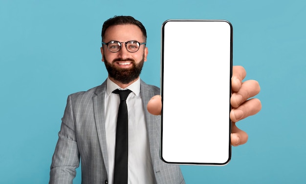 Mobile offer handsome businessman holding mobile phone with empty screen showing device with mockup