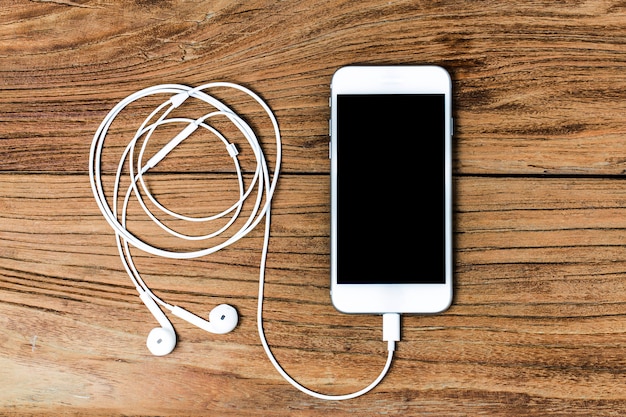 Mobile phone and earphones on wooden background