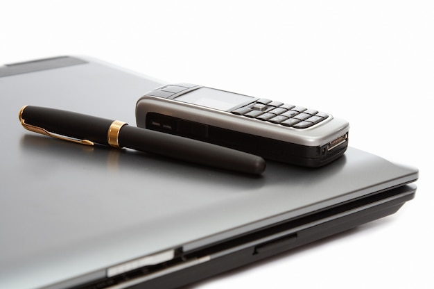 Mobile phone and fountain pen on the laptop