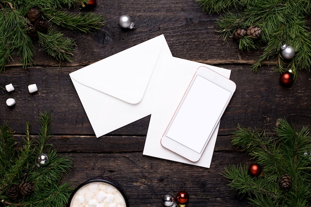 Mobile phone and postcard on a wooden table with a Christmas tree