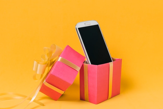 Mobile phone with blank screen in pink gift box