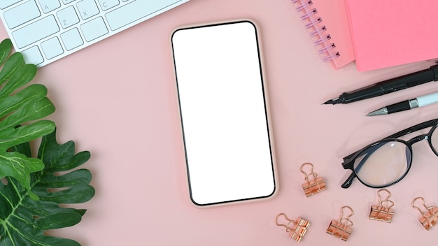 mobile phone with empty screen on feminine workspace. Flat lay.