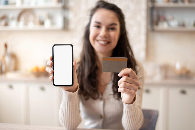 Mobile shopping application happy woman showing smartphone blank screen and credit card mockup