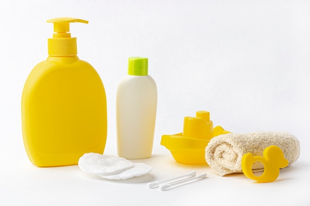 Mock up of baby bath products: bottles for shampoo (shower gel, lotion, oil), towel, cotton buds and pads on white background. Concept of baby bath accessories