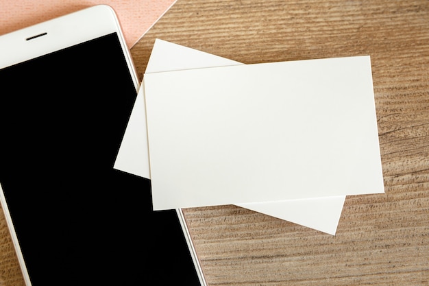 Mock up of blank business card and black smartphone screen on table