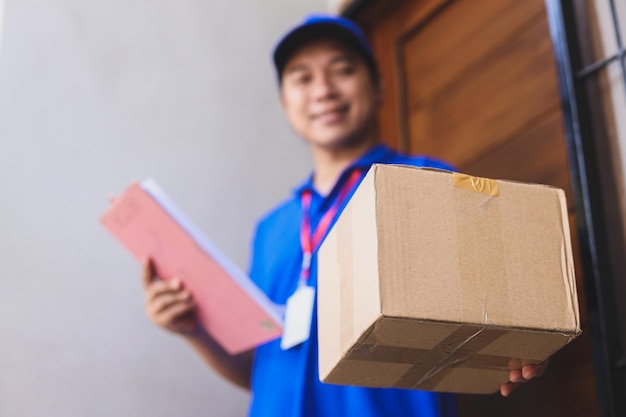 Mock up cardboard package with blurry image of deliveryman wearing blue uniform in front of the door