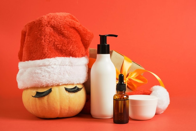 Mock up cosmetic bottles wrapped christmas gift and pumpkin in santa hat and false eyelashes