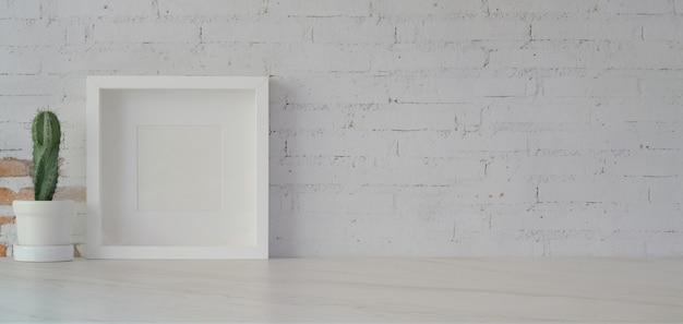 Mock up frame with cactus pot in minimal office room on white table and white brick wall