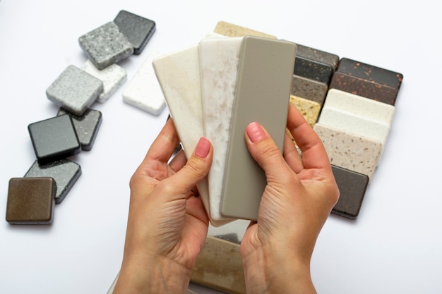 Mock up from natural stones, top view, close-up. Female hands advertises repair materials. Floor tiles, tiles, countertops.