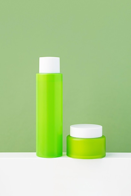 Mock up green cosmetic bottle and jar Minimal monochrome composition of skin care products