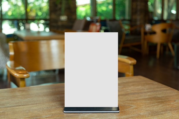 Mock up Label the blank menu frame in Bar restaurant. Stand for booklet with white sheet paper acrylic tent card on table wiht blurred background can inserting the text or picture