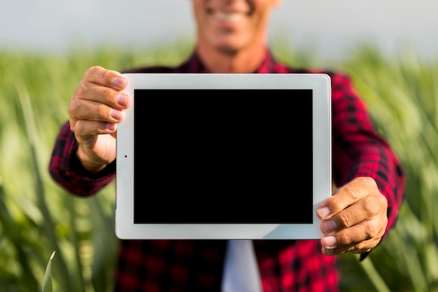 Mock-up man holding a tablet in a field