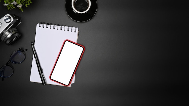 Mock up mobile phone notepad and coffee cup on black table