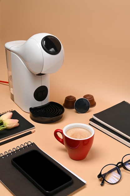 Mock up mobile phone red cup coffee machine and coffee capsules over on beige background