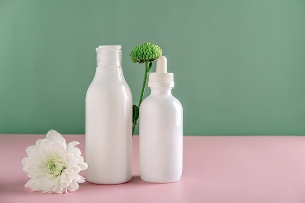 Mock up natural cosmetics: serum, cream, mask for advertising on green background with flowers. Organic products. Spa concept