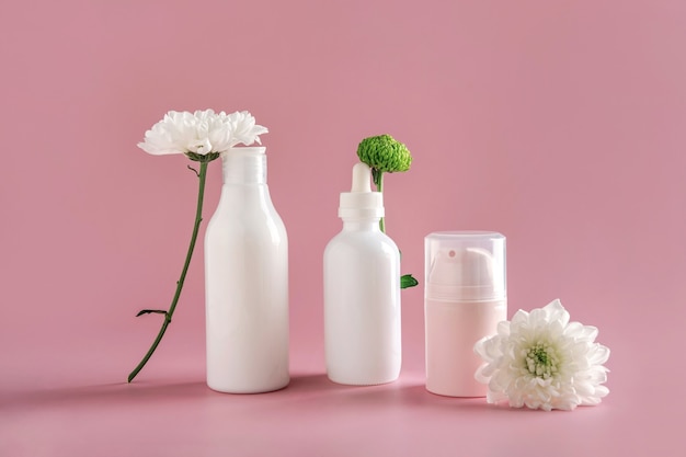 Mock up natural cosmetics: serum, cream, mask for advertising on light pink background with flowers. Organic products. Spa concept