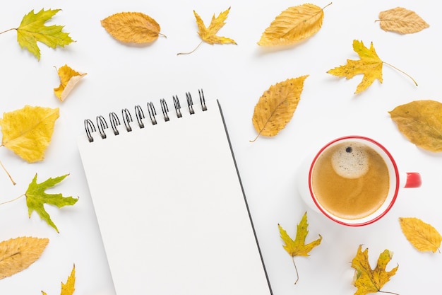 Mock up open sketchpad or notebook on artist desk workspace coffee and yellow autumn leaves on white