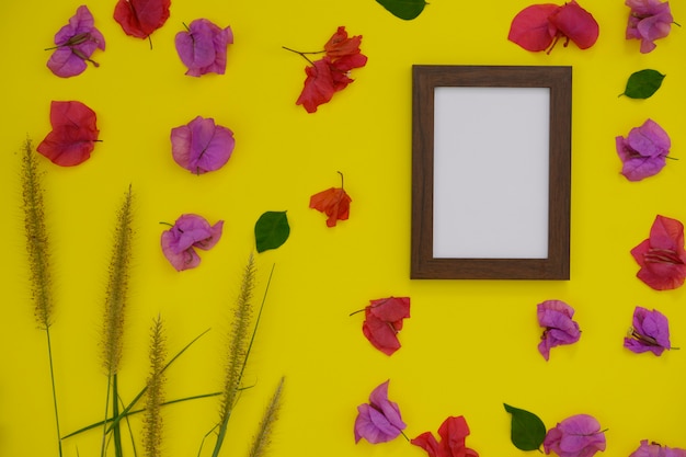 Mock-up photo frame with space for text or picture on yellow background and tropical flowers.