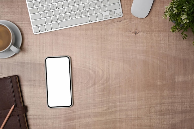 Mock up smart phone with white screen, notebook and coffee cup on wooden table.