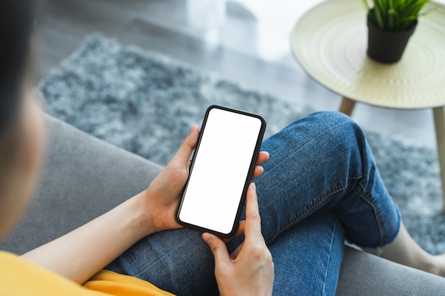 Mock up of woman hand holding smartphone and touching blank screen.