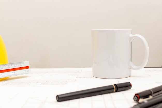 Mockup of architectural concept Drawing tool and coffee on drawing of blueprint with safety helmet