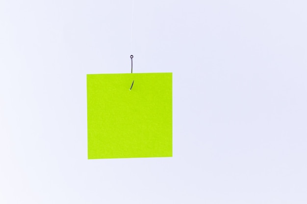 Mockup of a blank green memo paper with copy space hanging on a fishing hook