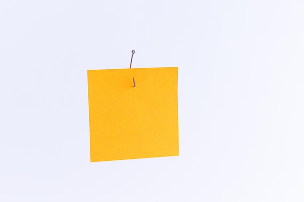 Mockup of a blank orange memo paper with copy space hanging on a fishing hook