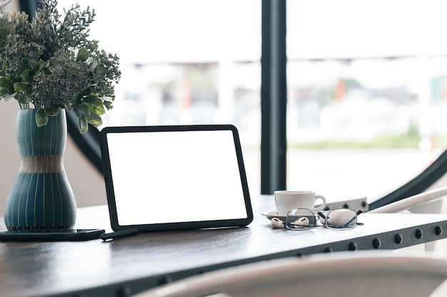 Mockup blank screen tablet and gadget on wooden table.