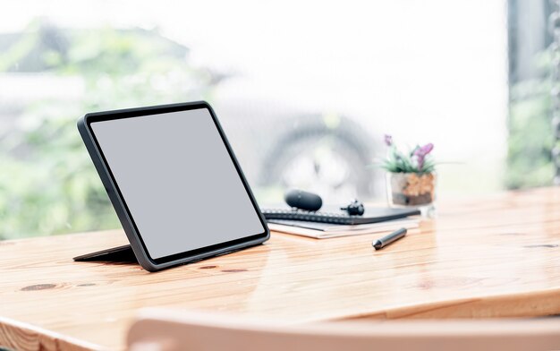 Mockup blank screen tablet and stylus pen on wooden table.