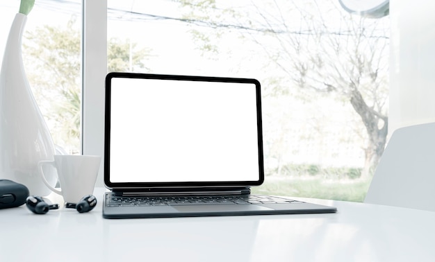 Mockup blank screen tablet with keyboard on white table in white office room.