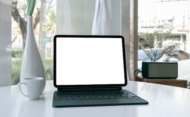 Mockup blank screen tablet with keyboard on white table.