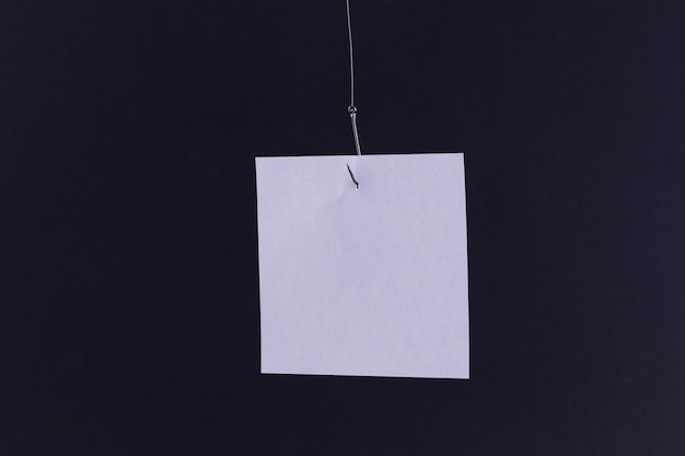 Mockup of a blank white memo paper with copy space hanging on a fishing hook