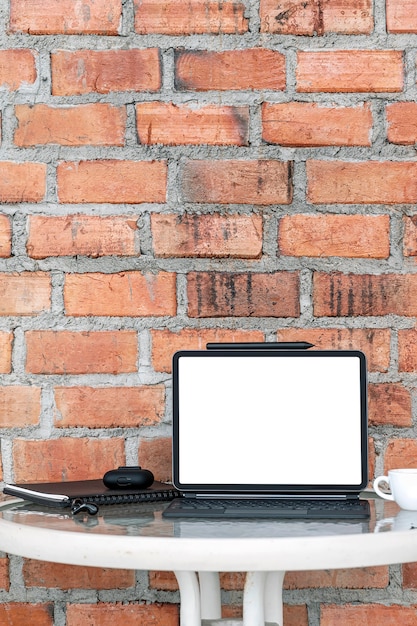 Mockup blank white screen tablet with magic keyboard and gadget on the table in vertical view.