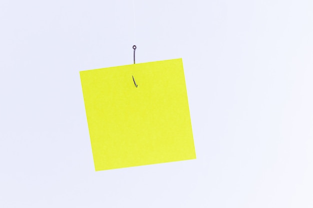 Mockup of a blank yellow memo paper with copy space hanging on a fishing hook